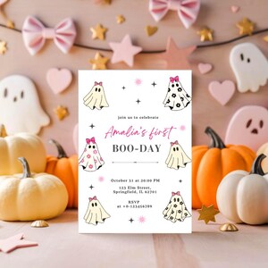 May include: A Halloween-themed invitation with ghost illustrations and the text "Amalia's first BOO-DAY." The invitation is surrounded by pumpkins, stars, and bows in shades of pink, gold, and white. The date and time are also included.