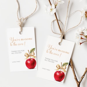 Può includere: Due etichette regalo bianche con illustrazioni di mele rosse e accenti di nastro dorato. Le etichette hanno il testo "You're awesome to the core!" e "Thank you for all you do!" con la firma "Love, Theo".
