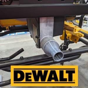 Puede incluir: Primer plano de un puerto de recolección de polvo gris en una sierra de mesa DeWalt negra y amarilla. El puerto está conectado a una manguera negra.