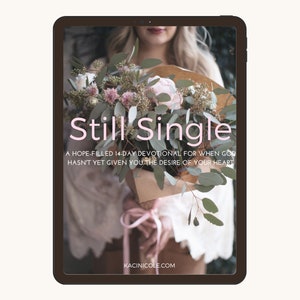 Op de afbeelding: Het scherm van een digitale tablet toont een boekomslag met de titel "Still Single" in roze tekst. De omslag toont een vrouw die een boeket bloemen vasthoudt en de tekst "A hope-filled 14-day devotional for when God hasn't yet given you the desire of your heart." en "KACINICOLE.COM".