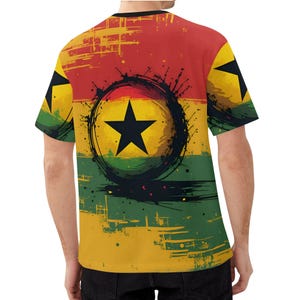 May include: A short-sleeved t-shirt featuring the Ghana flag design. The shirt has a red, yellow, and green background with a black star in the center. The design has a distressed, grunge-like appearance.