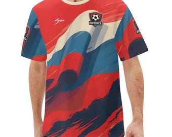 May include: Red, white, and blue graphic t-shirt with a soccer ball emblem that reads "Rossiya". The shirt has a crew neck and short sleeves. The design features abstract brushstrokes.