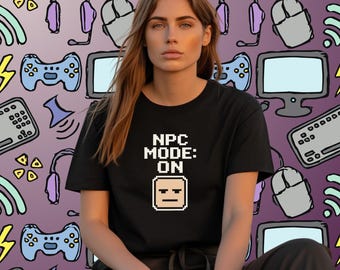 May include: Black t-shirt with the text "NPC MODE: ON" and a pixelated face graphic. The background features a pattern of gaming-related icons in shades of purple, grey, and blue, including headphones, controllers, and computer mice.
