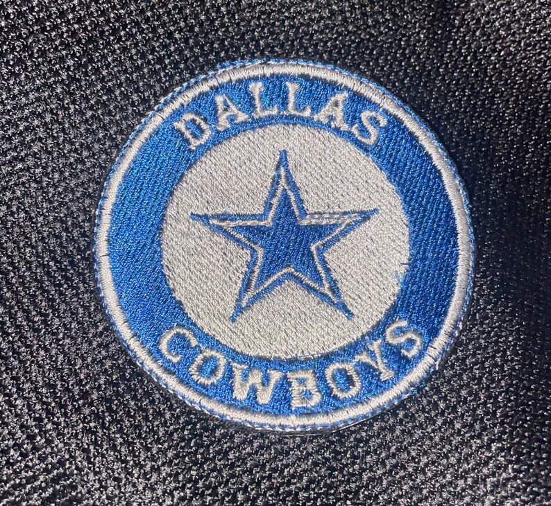May include: An embroidered patch featuring the words "Dallas Cowboys" and a five-pointed star, in blue and white.