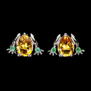 May include: A pair of silver frog earrings featuring pear-shaped yellow gemstones and smaller green gemstones for the eyes.