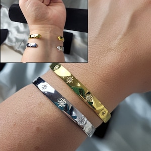 Peut inclure: Deux bracelets en or et en argent avec un motif d'étoile et de petites pierres claires. Les bracelets sont au poignet d'une personne.