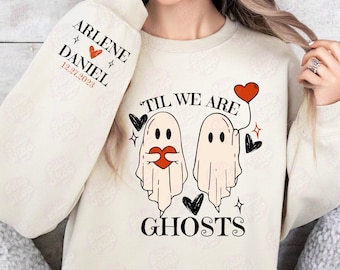 Może przedstawiać: Biała bluza z nadrukiem dwóch duchów trzymających serca. Pod duchami znajduje się napis "Til We Are Ghosts". Na rękawie nadrukowany jest tekst "Arlene Daniel 12.27.2023".