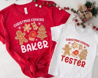 May include: Red and white Christmas cookie themed shirts. The red shirt says "Christmas Cookies Baker" and the white shirt says "Christmas Cookies Tester". Both shirts feature gingerbread men, snowflakes, bells, and Christmas trees.