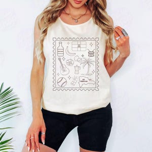 Pode incluir: Top sem mangas creme com um desenho de contorno preto de &iacute;cones da Rep&uacute;blica Dominicana dentro de uma borda de selo postal. O design inclui uma garrafa, banana, bandeira, tambor, guitarra, coco, palmeira, cafeteira, basebol e mapa.