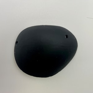 May include: A black, oval-shaped, rubber eye patch with two small holes.