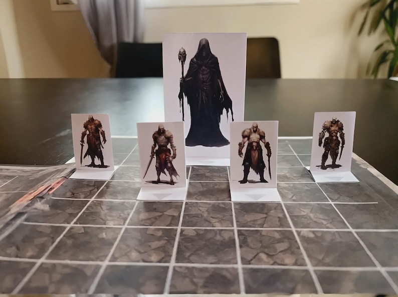 Puede incluir: Un conjunto de cinco miniaturas de papel para juegos de mesa con personajes de fantas&iacute;a, incluyendo cuatro guerreros con armadura y una figura central encapuchada con un bast&oacute;n, sobre un mapa de cuadr&iacute;cula con patr&oacute;n de piedra.