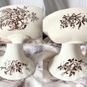 Pode incluir: Um suporte para bolo de cer&acirc;mica branca com um design floral castanho. O suporte tem uma borda ondulada e uma base larga.