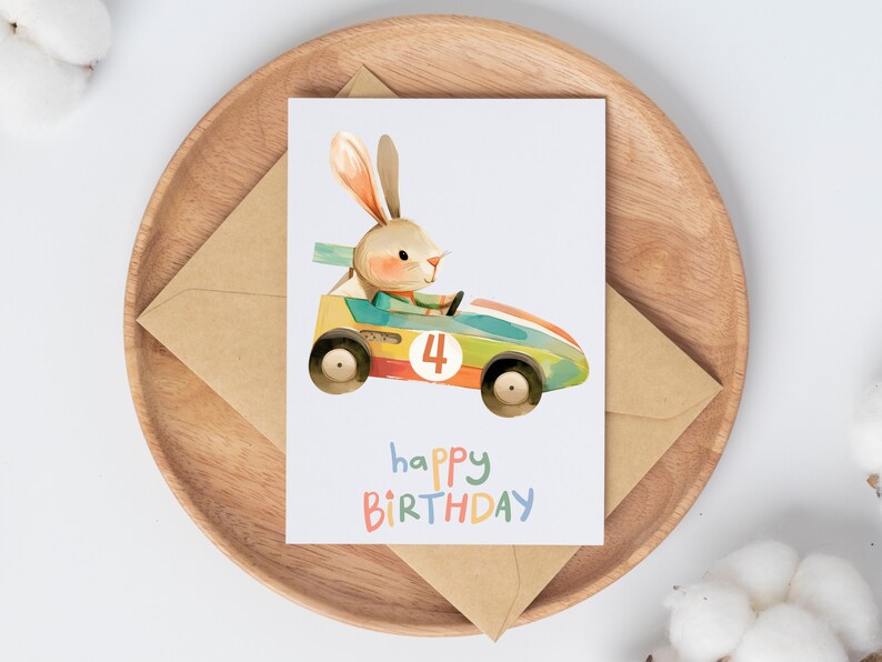 May include: A birthday card featuring a cartoon bunny driving a toy race car with the number 4 on the side. The card has the text "happy birthday" in colorful letters.