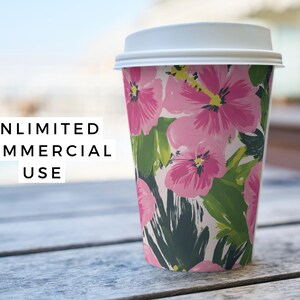 Puede incluir: Un vaso de papel blanco con un dise&ntilde;o floral con flores de hibisco rosas y hojas verdes. El vaso tiene una tapa blanca.