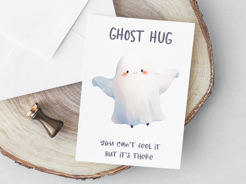 May include: A white ghost with a smiling face and outstretched arms, with the text "GHOST HUG" above and "you can't feel it but it's there" below.