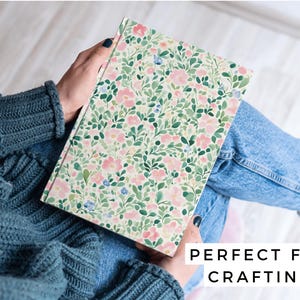 May include: A notebook with a floral pattern featuring pink and green flowers on a white background. The text "PERFECT FOR CRAFTING" is printed on the bottom of the image.