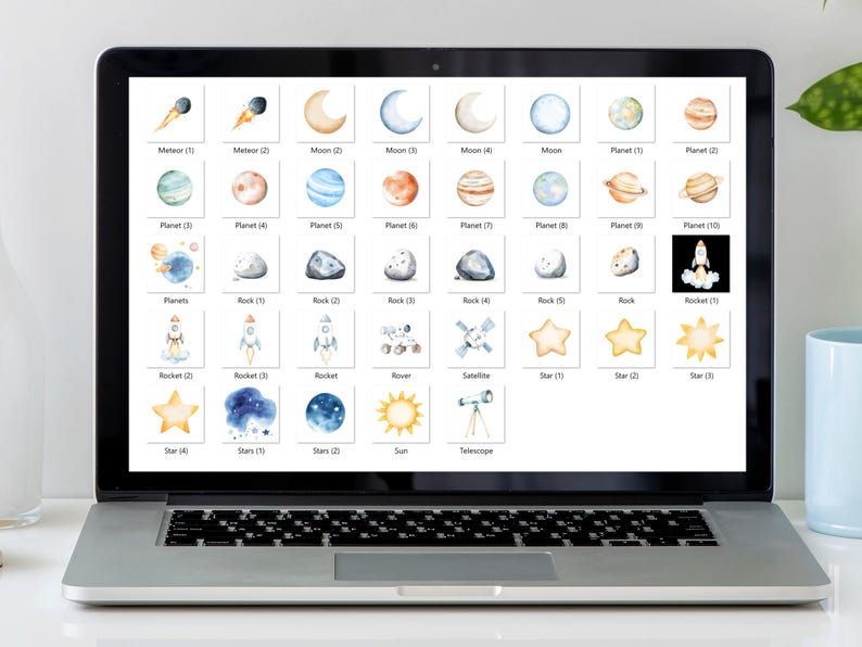 Puede incluir: Una pantalla digital que muestra una variedad de ilustraciones de acuarela de objetos con tem&aacute;tica espacial, incluidos planetas, estrellas, cohetes y un rover. Las ilustraciones est&aacute;n organizadas en un formato de cuadr&iacute;cula con etiquetas debajo de cada imagen.