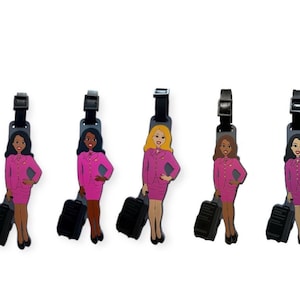 May include: Five colorful luggage tags featuring a cartoon female flight attendant in a pink uniform holding a suitcase. The tags are black with a silver buckle.