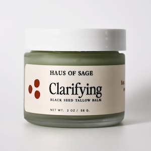 Könnte beinhalten: Ein Glas Haus of Sage Clarifying Black Seed Tallow Balm. Das Glas hat einen weißen Deckel und ein Etikett mit Produktname und Marke. Nettogewicht: 56 g.