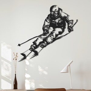 Könnte beinhalten: Schwarze und weiße Silhouette Wandaufkleber eines Skifahrers in der Luft, mit Skiern und Stöcken, an einer weißen Wand mit einem Holztisch und Stuhl im Vordergrund.