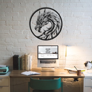 May include: A black metal dragon wall art piece, circular in shape, mounted on a white brick wall. The dragon is depicted in profile, with intricate details. The image is of a desk with a laptop, books, and a typewriter.