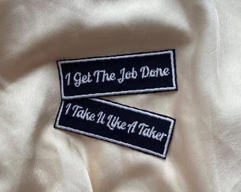 Peut inclure: Deux patchs thermocollants brodés noirs avec du texte blanc. Le patch du haut indique "I Get The Job Done". Le patch du bas indique "I Take It Like A Taker".