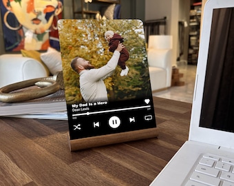 May include: A wooden photo frame with a digital music player interface. The photo shows a father holding his child up in the air. The music player interface displays the song title "My Dad Is a Hero" by Dean Lewis.