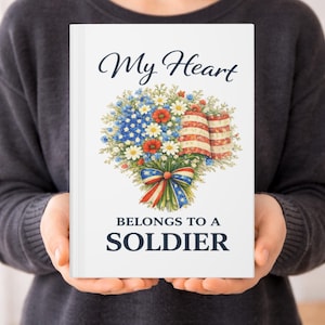 May include: A white journal with the text "My Heart Belongs to a Soldier." The cover features a floral design with red, white, and blue elements, including an American flag motif and a patriotic bow.