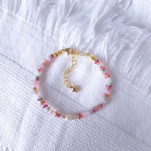 May include: A colourful beaded bracelet with pink, green, and orange beads. The bracelet has a gold-coloured chain and clasp, with a small star charm. The beads are strung together, creating a charming accessory. The bracelet is suitable for a wrist size of approximately 15 cm.