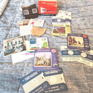 Puede incluir: Una colección de artículos View-Master vintage, que incluye un visor marrón, cajas rojas y blancas, y varios carretes y folletos. Los folletos presentan imágenes de Florida, Disneyland y vaqueros.