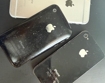 May include: Three smartphones including one silver iPhone 6s and two black iPhones. Each device features the Apple logo on the back, a rear camera lens, and printed text including the word iPhone, regulatory markings, and storage capacity details.