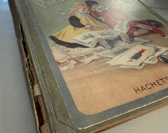 May include: Vintage children's book titled "Mon Premier Alphabet" with a cover illustration of two children reading. The book has a distressed cover with a green spine and a light blue border. The publisher's name, HACHETTE, is visible.