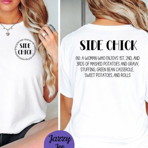 May include: White t-shirt with a black circle graphic that says "Side Chick" and a definition of the term. The back of the shirt has the definition of "Side Chick" printed on it. The shirt is being modeled by a person.