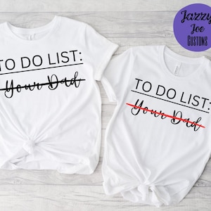 Puede incluir: Dos camisetas blancas con el texto "TO DO LIST: Your Dad" impreso en ellas. La palabra "Dad" está tachada en ambas camisetas.
