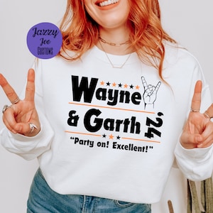 May include: White sweatshirt with black text that reads "Wayne & Garth '92" with five stars above the name and three stars below the name. The text "Party on! Excellent!" is below the name and date. A hand with a rock and roll hand gesture is to the right of the name.