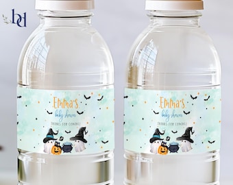 Puede incluir: Dos botellas de agua de plástico transparente con etiquetas azules y naranjas. Las etiquetas presentan un fondo de acuarela con murciélagos, estrellas y el texto "Emma's baby shower Thanks for coming!"  Las etiquetas también presentan una ilustración de dibujos animados de dos fantasmas, una caldera y una calabaza.