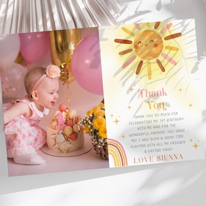 Puede incluir: Una tarjeta de agradecimiento rosa y amarilla con una ilustración de un sol sonriente. El texto dice "Gracias" e incluye un mensaje agradeciendo a los invitados por celebrar un primer cumpleaños. Una foto de una niña pequeña con un vestido rosa está en el fondo.