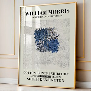 May include: A framed art print featuring a floral design in shades of blue and white, with the text "WILLIAM MORRIS" and "COTTON PRINTS EXHIBITION". The print is displayed in a gold frame.