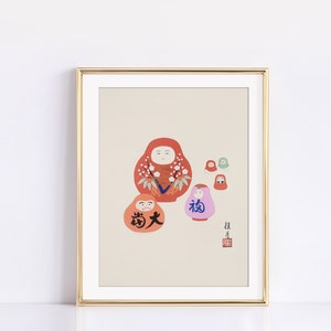 May include: Framed art print featuring a collection of Daruma dolls in shades of red, orange, and pink, with Japanese characters. The dolls have white facial features and floral accents. The print is in a gold frame.