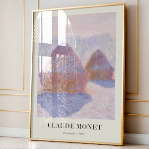 May include: A framed print of a painting by Claude Monet titled "Haystacks" from 1891. The painting depicts a landscape with haystacks in the foreground and a hazy, purple sky in the background.