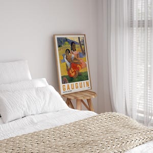 May include: A framed print of a Gauguin painting, featuring two women in colorful attire. The artwork has a warm color palette with reds, oranges, and yellows. The print is displayed on a small wooden stool in a bedroom setting.