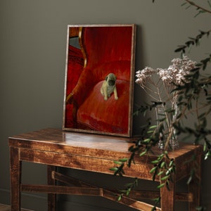 Puede incluir: Una impresi&oacute;n enmarcada con un cachorro de pug sentado en un sill&oacute;n de terciopelo rojo. La impresi&oacute;n tiene un marco de madera y se exhibe sobre una mesa de madera oscura. El cachorro tiene un pelaje marr&oacute;n claro y una cara negra. El fondo es una pared verde oscuro.