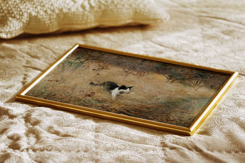 K&ouml;nnte beinhalten: Ein gerahmtes Kunstwerk mit einer schwarz-wei&szlig;en Katze in einem Feld mit hohem Gras. Das Gem&auml;lde hat einen goldenen Rahmen und liegt auf einer cremefarbenen, gemusterten Oberfl&auml;che. Das Kunstwerk zeigt eine Katze in einer nat&uuml;rlichen Umgebung.