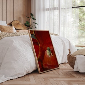 Puede incluir: Una impresi&oacute;n enmarcada que presenta un cachorro pug descansando sobre una silla roja tapizada. La impresi&oacute;n tiene un marco de madera y est&aacute; apoyada contra una cama con ropa de cama blanca. La habitaci&oacute;n tiene pisos de madera y una ventana con persianas.