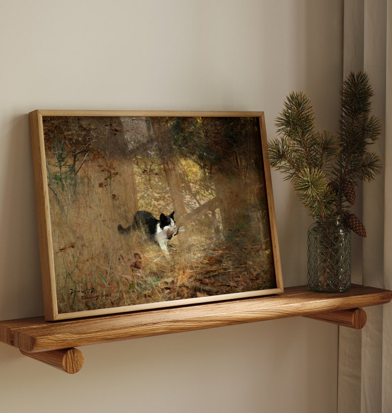 K&ouml;nnte beinhalten: Gerahmter Kunstdruck mit einer schwarz-wei&szlig;en Katze in einer Waldszene, die Beute tr&auml;gt. Das Kunstwerk befindet sich in einem Holzrahmen und steht auf einem Holzregal. Rechts befindet sich eine Glasvase mit Kiefernzweigen und Zapfen.