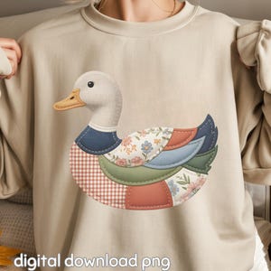 May include: A beige sweatshirt featuring a patchwork duck design. The duck has a white head, a yellow beak, and a body composed of various fabric patterns, including floral, gingham, and solid colors. The text "digital download png" is at the bottom.