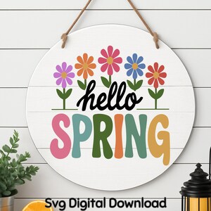 May include: A round, white wooden sign with the words "hello SPRING" in colorful letters. Above the text are six colorful flowers. The sign is hanging by a brown rope. The sign is a digital download.