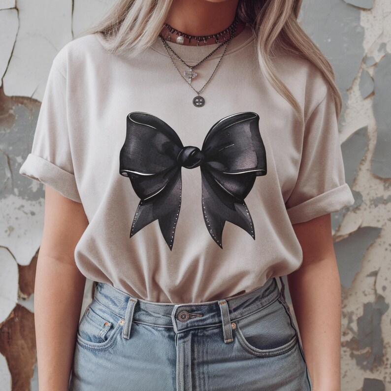May include: A light beige t-shirt with a large black bow graphic printed on the front.