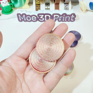 May include: Two round, multi-layered, pink and gold, glitter-covered, decorative coasters.