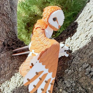 May include: A brown and white barn owl figurine with detailed feathers and a realistic appearance. The owl is perched on a tree branch.